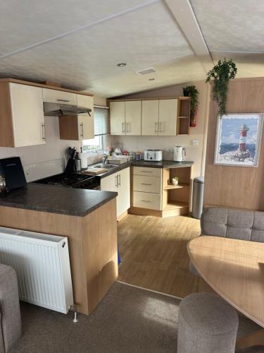 a large kitchen with a counter and a table at Phoenix caravan hire, Trecco bay in Porthcawl
