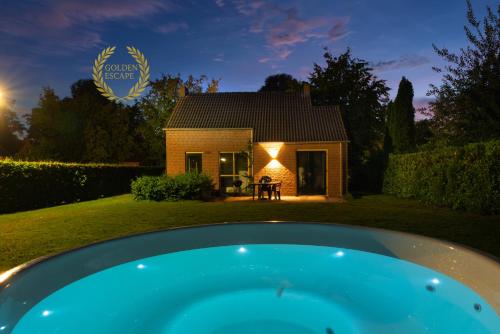 a house with a pool in the yard at night at Goldenescape 6P Vip cottage met royale tuin en Hottub in Ewijk