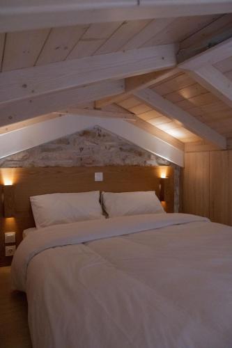 a large white bed in a room with wooden ceilings at Μικρό σαλέ. in Pournára