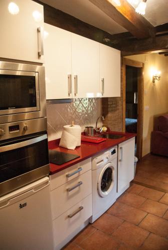 a kitchen with white cabinets and a washer and dryer at El Mijolar Apartamentos in Armaño