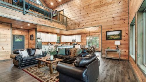 a living room with leather furniture and a kitchen at Smoky Horizon by AvantStay Game Room Movie Theater Deck w Hot Tub Views in Sevierville