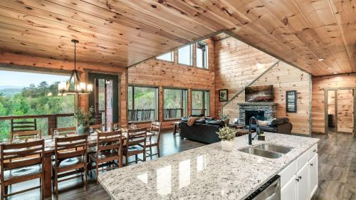 a kitchen and living room of a log cabin at Smoky Horizon by AvantStay Game Room Movie Theater Deck w Hot Tub Views in Sevierville