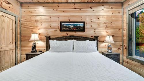 a bedroom with a bed in a wooden wall at Smoky Horizon by AvantStay Game Room Movie Theater Deck w Hot Tub Views in Sevierville