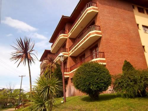 un edificio alto de ladrillo con una palmera junto al Aparte Familiar Antu Alen I en Villa Gesell