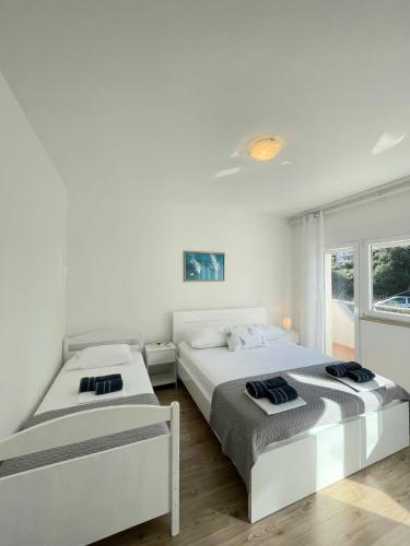 a white bedroom with two beds and a window at Apartman & rooms Draga in Marina