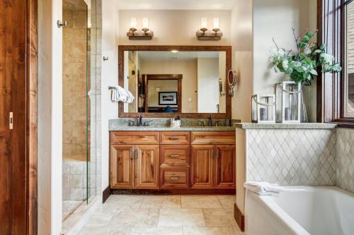 a bathroom with a tub and a sink and a mirror at Crystal Peak Lodge, A Vail Resorts Property in Breckenridge