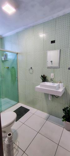 a green tiled bathroom with a sink and a shower at Apto no coração de Serra Negra in Serra Negra