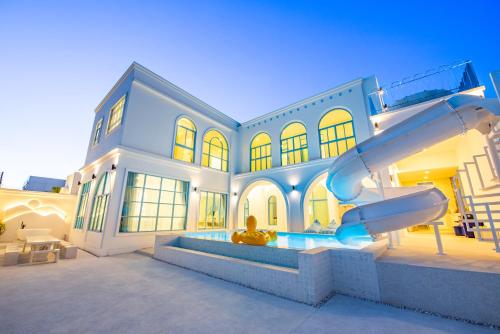 a man sitting in front of a house with a slide at Blue Tierra Pool Villa Pattaya in Ban Hua Phrong