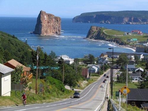 una persona montando en bicicleta en una carretera junto al océano en Motel le repos, en Percé