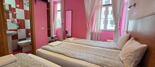 a pink bedroom with two beds and a toilet at Baixa GuestHouse in Lisbon