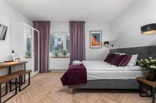 a bedroom with a large bed with purple curtains at AURA 77 Żoliborz in Warsaw