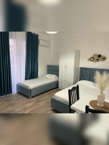 a room with two beds and a table and a table and chairs at Marra’s Rooms in Durrës