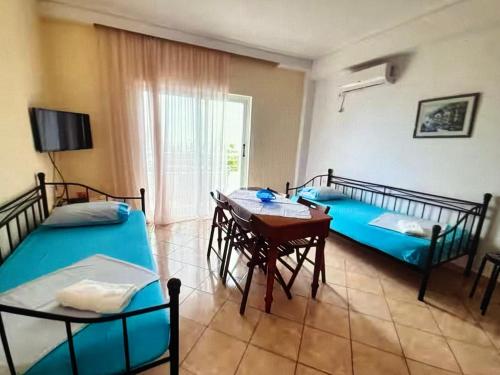 a room with two beds and a table and chairs at Sea View in Dhermi in Gjilek
