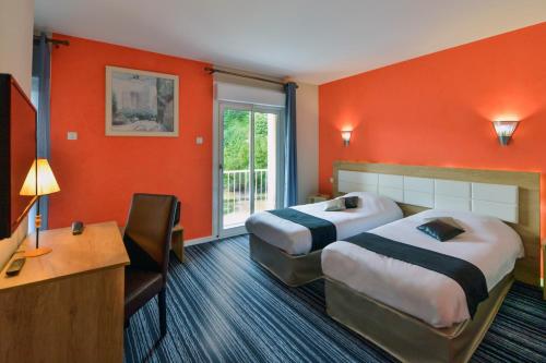 two beds in a hotel room with orange walls at Contact Hotel Le Moulin Neuf Chantonnay in Chantonnay