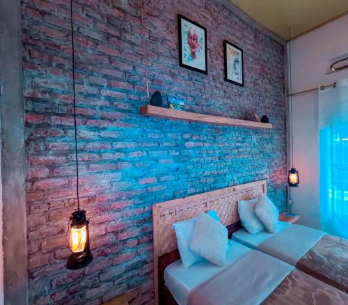 a bedroom with a brick wall and a bed with pillows at Saish Stay in Ruhengeri