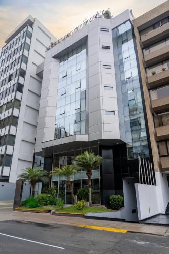 a tall white building with palm trees in front of it at Jose Antonio Executive in Lima