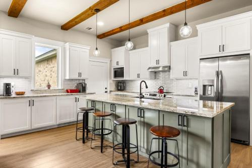 a kitchen with white cabinets and bar stools at NEW Stunning Views & Lake Access Villa in Granbury