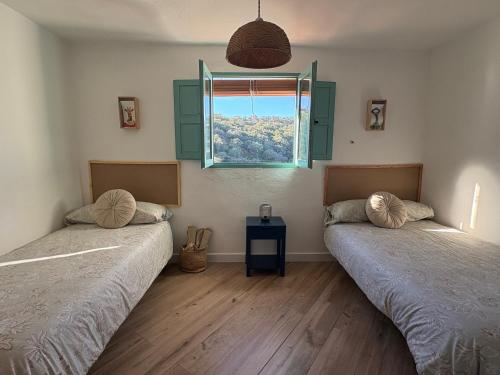 two beds in a room with a window at Alojamiento La Casa del Pintor in Almonaster la Real