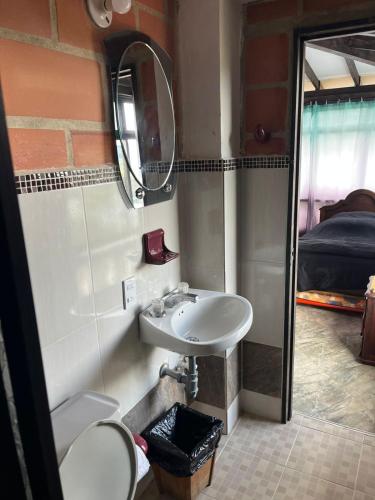 a bathroom with a sink and a mirror and a bed at Hotel Montañitas in Guatapé