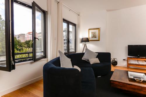 a living room with a black couch and windows at Center Gardens Apartments in Lisbon