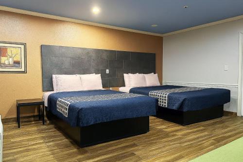 a hotel room with two beds with blue sheets at Downtowner Inns & Suites IAH Airport - Humble TX US 59 in Humble