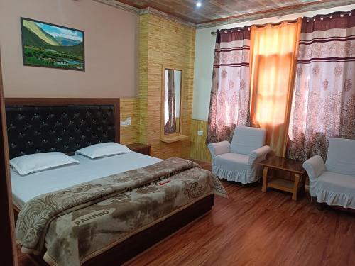 a bedroom with a large bed and two chairs at Apple Bud Homestay in Ghund