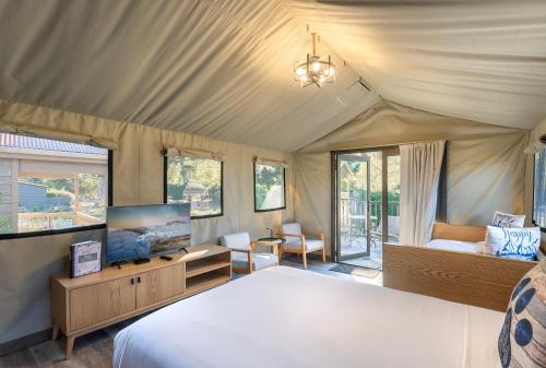 a bedroom with a bed and a tv in a tent at Carmel River Inn & Cottages in Carmel
