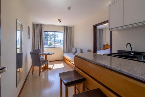 a kitchen and living room with a counter top and a room at Hotel Flat Petras Residence in Curitiba