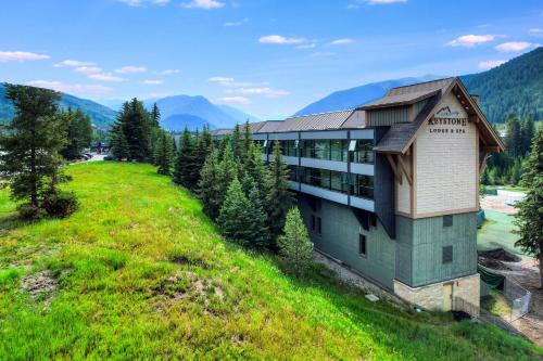 a building on a grassy hill with mountains in the background at Keystone Lodge & Spa, A Vail Resorts Property in Keystone