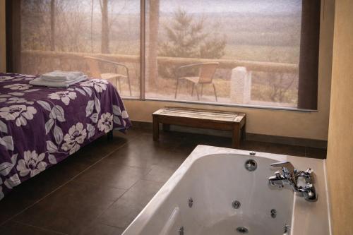 a bathroom with a tub and a bed and a window at Casas Rurales Los Cortijos in Alcaraz
