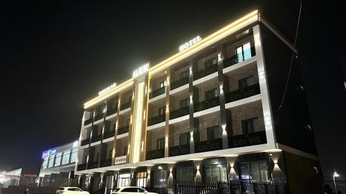 a lit up building with cars parked in front of it at Alatau hotel in Shymkent