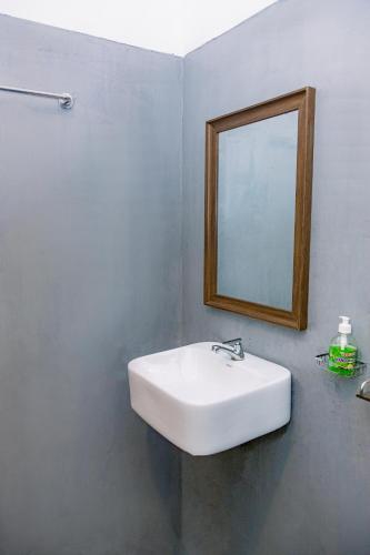 a bathroom with a white sink and a mirror at Lazy Monkey Green Chalets in Hiriketiya