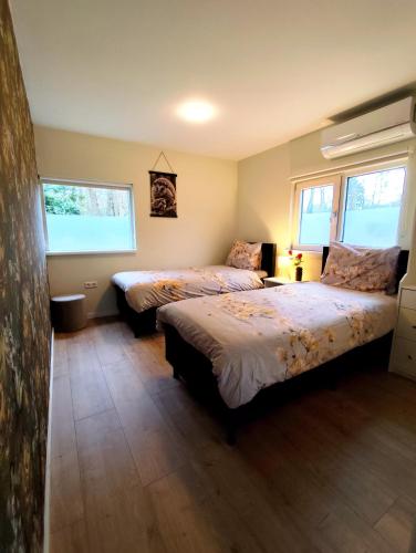 a bedroom with two beds and two windows at Morning Glory, huisje Forest in Beekbergen