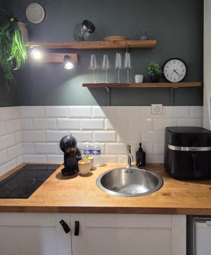 a kitchen counter with a sink and a clock at Studio - Le Cocon in Saint-Brieuc