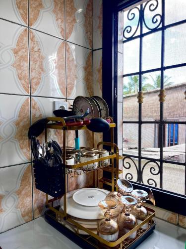 Un estante con platos y cuencos junto a una ventana. en Golden Apartment, en Douala