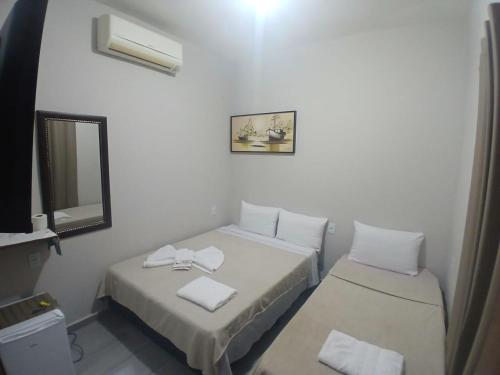 a small room with two beds and a mirror at Pousada Milagres de Maria in Aparecida