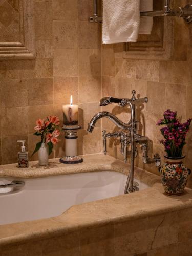 a bathroom with a bath tub with a candle and flowers at Monasterio, A Belmond Hotel, Cusco in Cusco