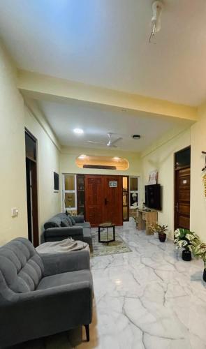 a living room with two couches and a television at Vaadhee Homestay in Guraidhoo