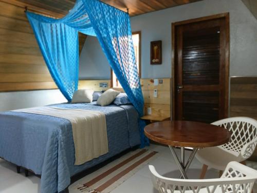 a bedroom with a blue bed and a table at Hotel Cajuína Beach in Parnaíba