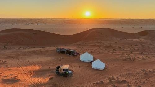 two tents in the desert with the sunset in the background at Just For You Starwatching Tent in Al Wāşil