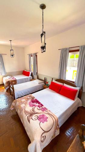 a bedroom with three beds with red pillows at POUSADA PARLATORIUM in Tiradentes