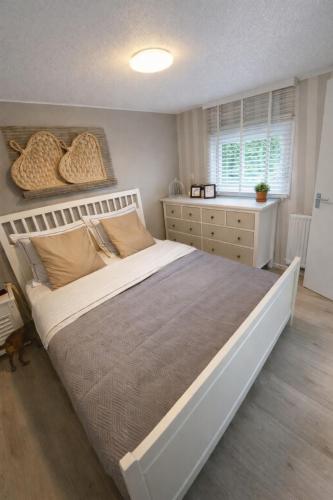 a bedroom with a large bed and a dresser at Luxe Chalet met prachtig terras op de Veluwe , veel privacy in Hoenderloo