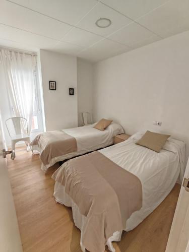 two beds in a white bedroom with a window at Boutique 2 apartamento Ave centro Lleida in Lleida