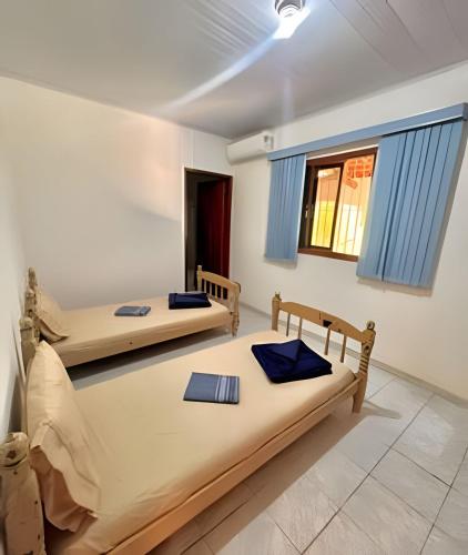two beds in a room with blue curtains at Refúgio na natureza com piscina e churrasqueira in Pedro de Toledo