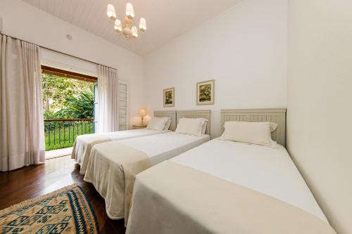 two beds in a room with a window at Fazenda Santanna Hotel in Amparo