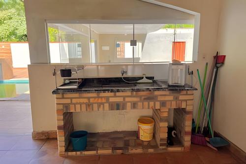 a kitchen with a brick fireplace with a sink at Refúgio na natureza com piscina e churrasqueira in Pedro de Toledo