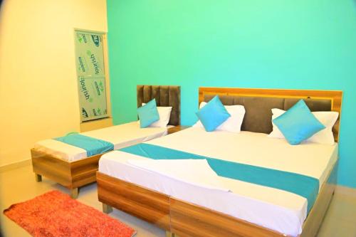 a bedroom with two beds and a blue wall at Vatika palace in Ayodhya