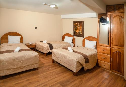 a room with two beds and a dresser at Hotel Melanys in Cusco