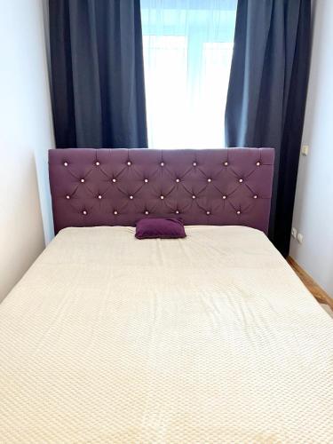 a bed with a purple headboard in a bedroom at Центр, 2х комнатная студио возле парка, WIFI in Vinnytsya