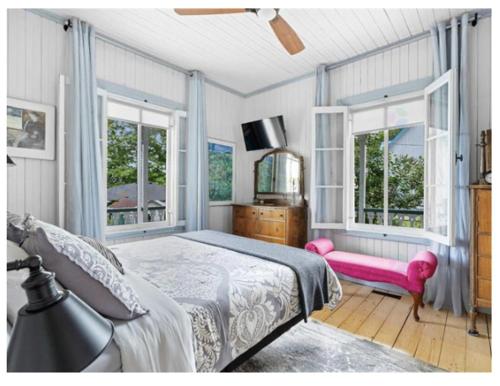 a bedroom with a bed and a pink chair at La maison de l'île d'Orléans - B&B - déjeuner gastronomique in Saint-Jean